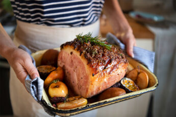 A mature woman serving a roast ham in a baking pan