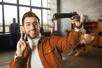 Smiling man trying to take a selfie on an old-fashioned phone handset